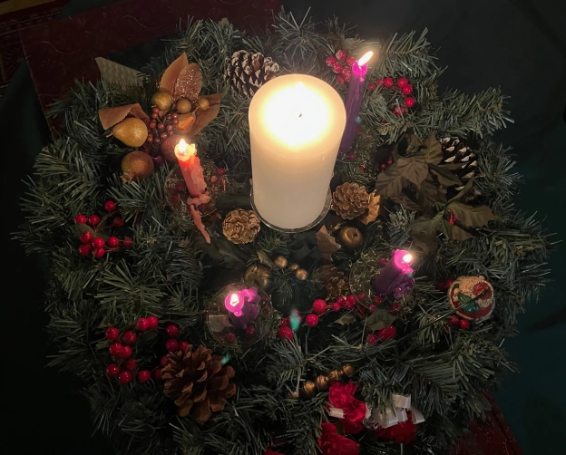 Advent wreath with all candles lit and Christ Candle glowing in the center